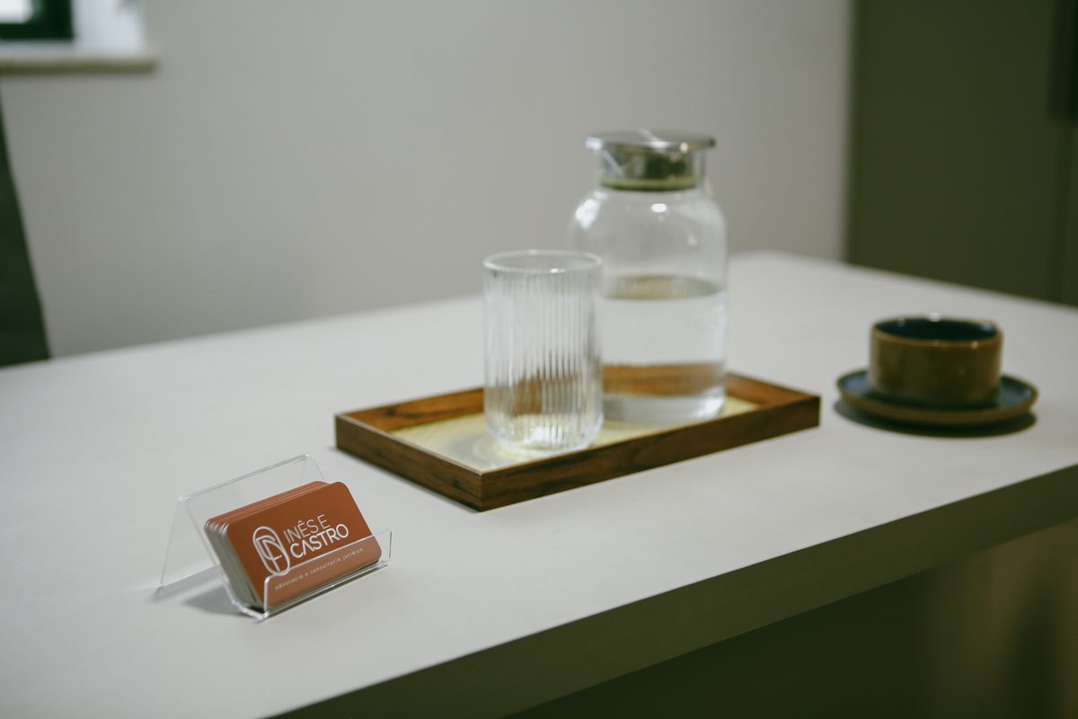 Detalhe da mesa com cartões de visita e jarra de água